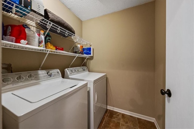 washroom with dark tile patterned floors, a textured ceiling, separate washer and dryer, baseboards, and laundry area