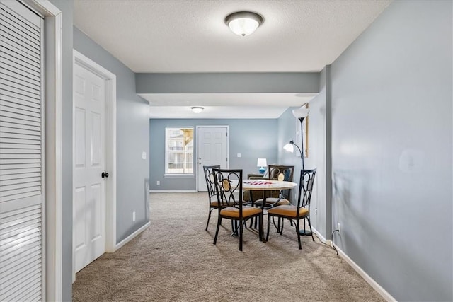 dining room featuring baseboards, a textured ceiling, and carpet