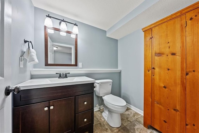 half bath with baseboards, toilet, and vanity