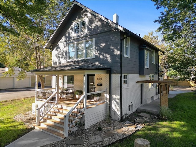 view of front of property with a porch, an outdoor structure, a garage, brick siding, and a chimney