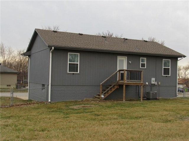 back of house featuring central AC unit, roof with shingles, a yard, and fence