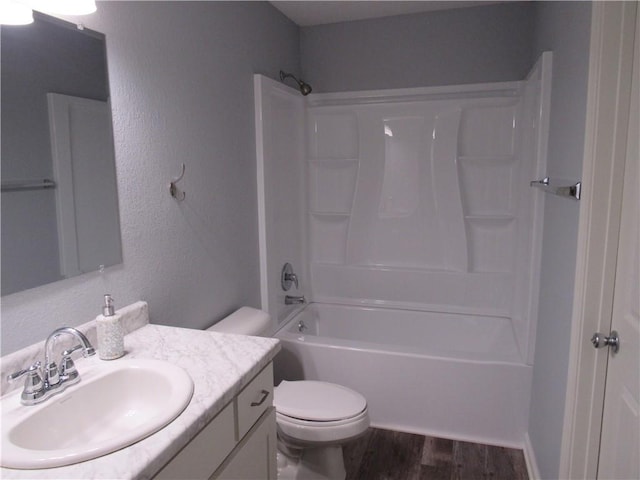 bathroom featuring vanity, wood finished floors, tub / shower combination, toilet, and a textured wall