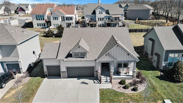 view of front facade with a residential view, board and batten siding, driveway, and stone siding