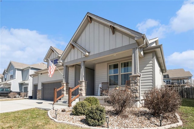 view of front of house with board and batten siding, a porch, driveway, stone siding, and an attached garage