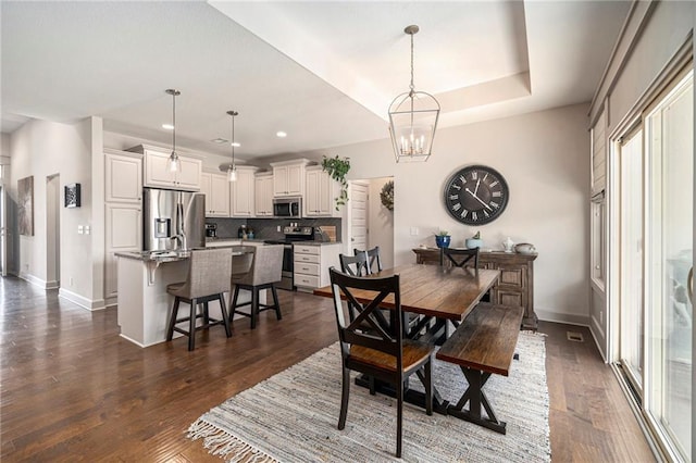 dining room with dark wood-style floors, baseboards, recessed lighting, a raised ceiling, and a notable chandelier