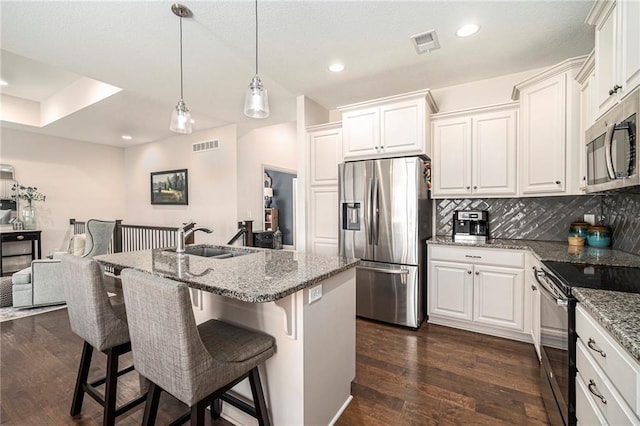 kitchen with visible vents, dark wood finished floors, a sink, stainless steel appliances, and tasteful backsplash