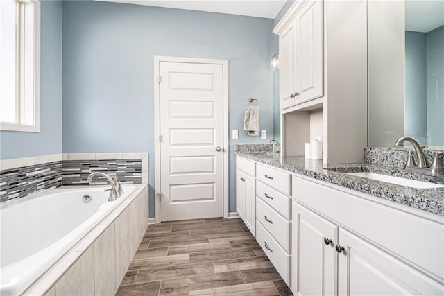 bathroom featuring a sink, wood finish floors, a garden tub, and double vanity