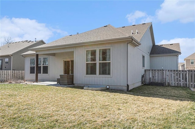 rear view of property with a shingled roof, a lawn, a fenced backyard, and a patio area