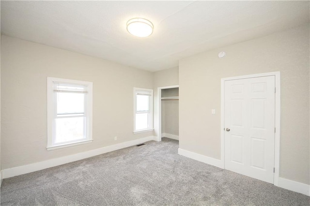 unfurnished bedroom with a closet, carpet flooring, visible vents, and baseboards