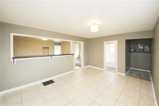 empty room featuring light tile patterned flooring, visible vents, and baseboards