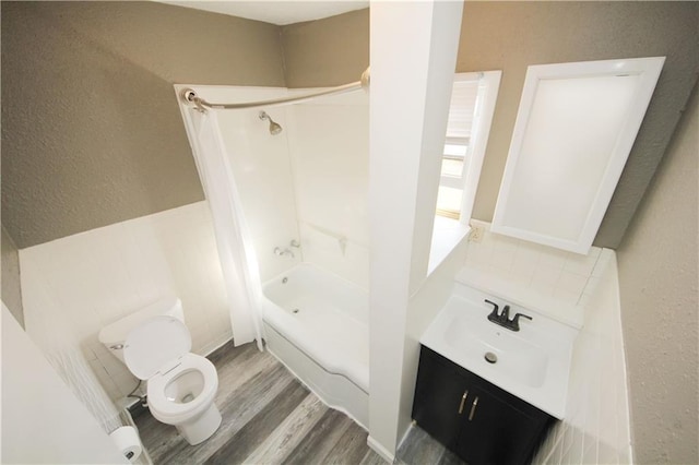 bathroom featuring toilet, wood finished floors, bathtub / shower combination, vanity, and a textured wall