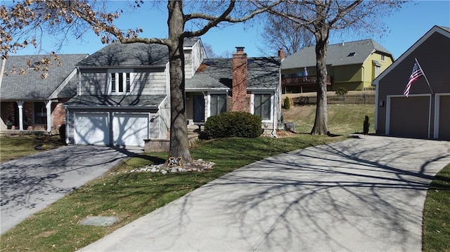 view of front of house with an attached garage, a front yard, a chimney, and driveway