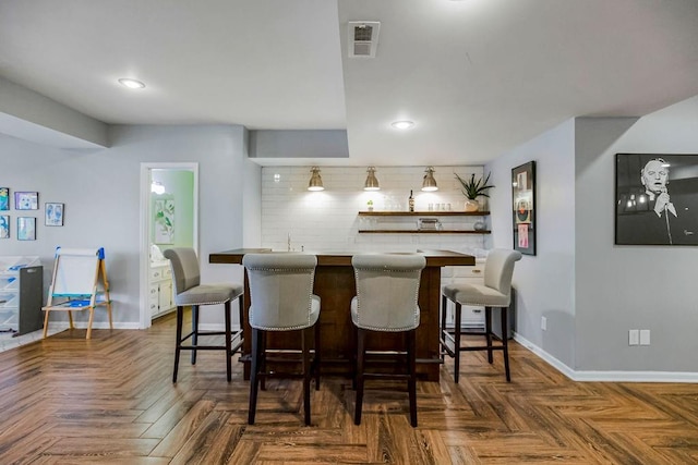 interior space with visible vents, a breakfast bar area, baseboards, and decorative backsplash