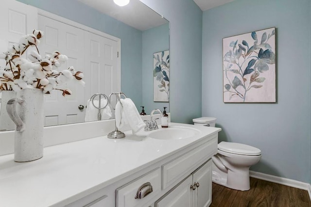 bathroom with vanity, toilet, wood finished floors, and baseboards