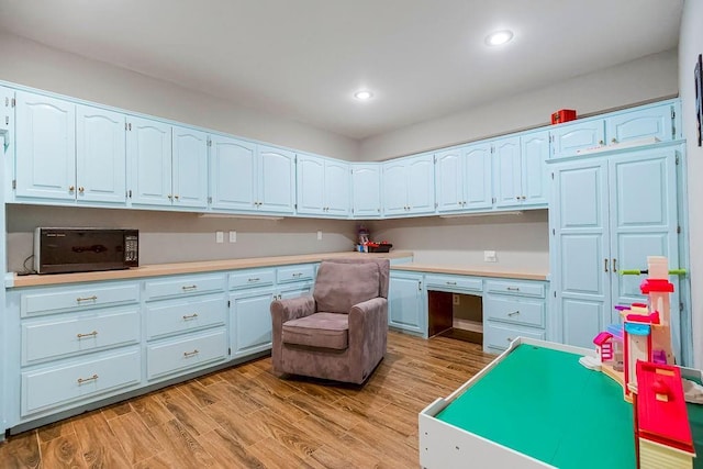 interior space with light countertops, recessed lighting, built in desk, and light wood-type flooring