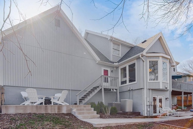 view of front of house featuring central air condition unit, french doors, a patio, and roof with shingles