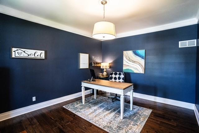 office featuring visible vents, baseboards, crown molding, and wood finished floors