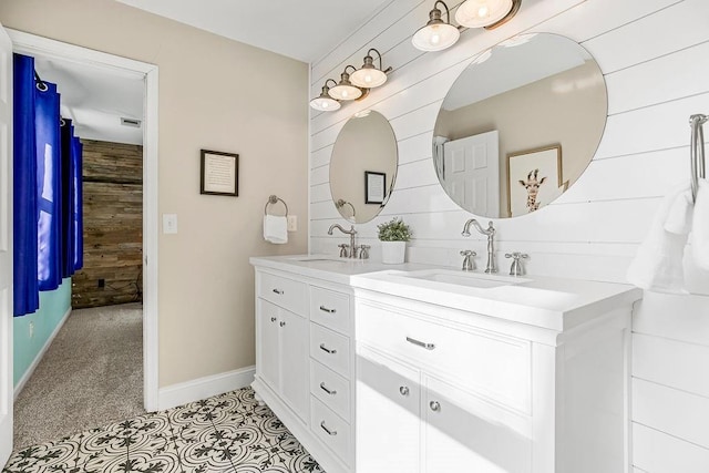 bathroom with baseboards, a sink, wooden walls, and double vanity