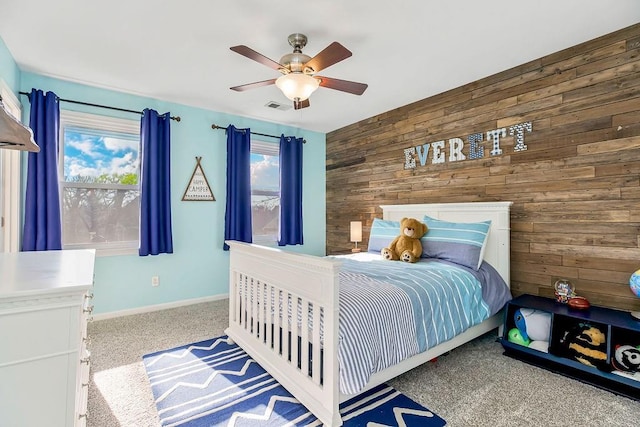 bedroom featuring ceiling fan, visible vents, baseboards, wooden walls, and carpet