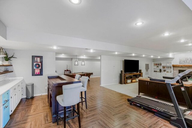 interior space with a center island, recessed lighting, open floor plan, baseboards, and a kitchen bar