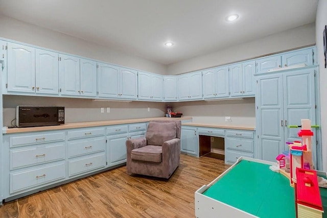 interior space with built in study area, recessed lighting, and light wood finished floors