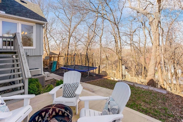 view of patio featuring central AC, fence, a fire pit, and a trampoline