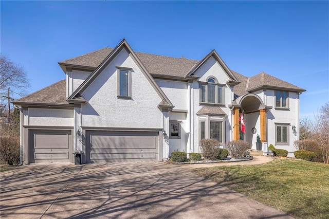 view of front of house featuring stucco siding, a front yard, a garage, and driveway