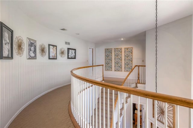 corridor featuring an upstairs landing, visible vents, baseboards, and carpet