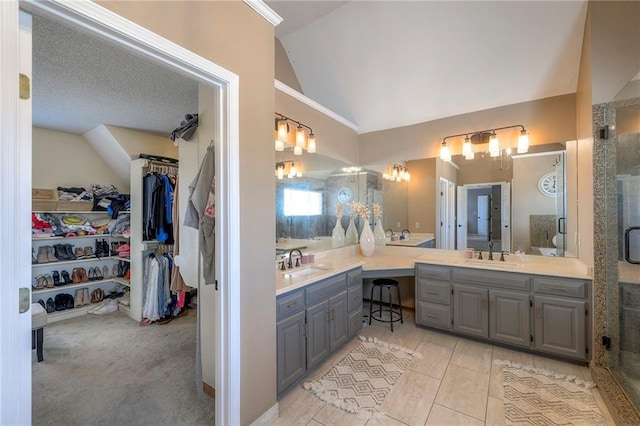 bathroom featuring a sink, lofted ceiling, two vanities, and a stall shower