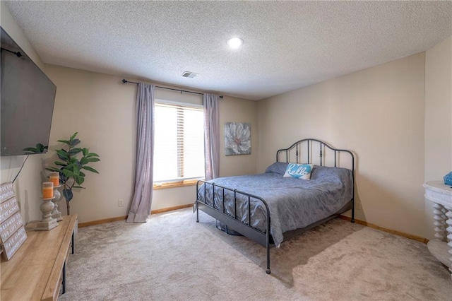 bedroom featuring a textured ceiling, baseboards, and light carpet