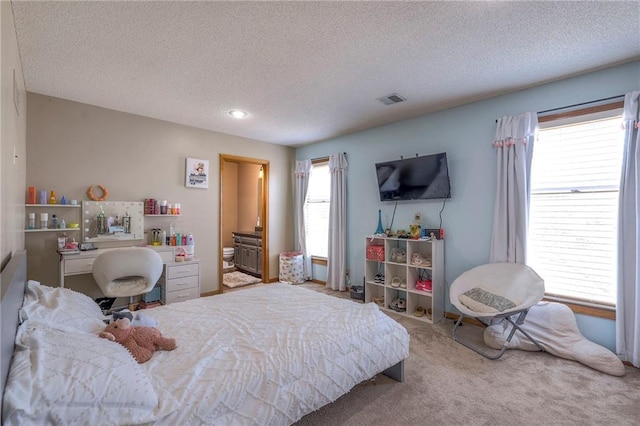 bedroom featuring carpet flooring, visible vents, connected bathroom, and a textured ceiling