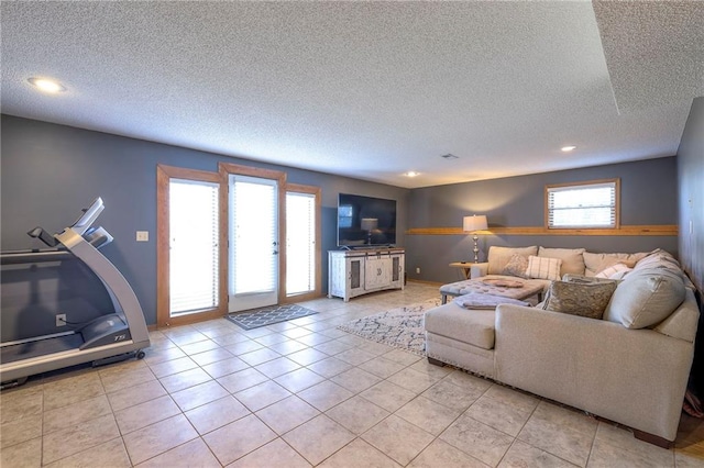 living area with light tile patterned floors, a textured ceiling, and a healthy amount of sunlight