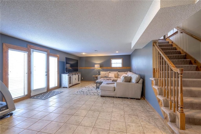 living area with stairway, light tile patterned flooring, a wealth of natural light, and a textured ceiling