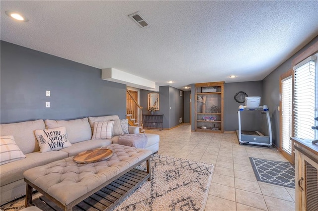 living room featuring visible vents, baseboards, stairs, light tile patterned floors, and a textured ceiling