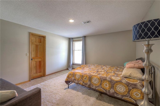 bedroom featuring tile patterned floors, visible vents, baseboards, and a textured ceiling