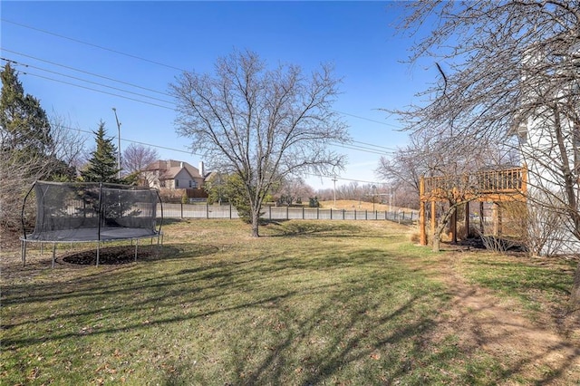 view of yard featuring a wooden deck, a trampoline, and fence