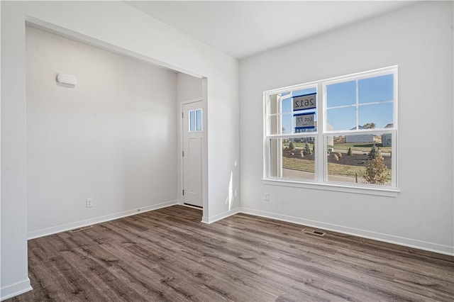 empty room with visible vents, baseboards, and wood finished floors