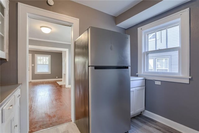 kitchen featuring baseboards, freestanding refrigerator, light countertops, white cabinets, and light wood-type flooring