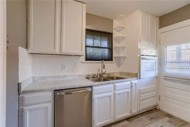 kitchen with oven, a sink, light countertops, white cabinets, and dishwasher