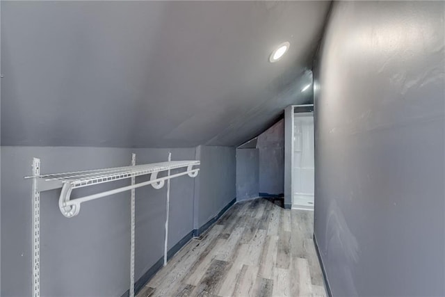 walk in closet with light wood-type flooring and lofted ceiling