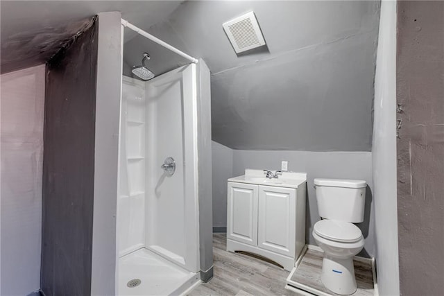 bathroom with wood finished floors, visible vents, lofted ceiling, a stall shower, and toilet