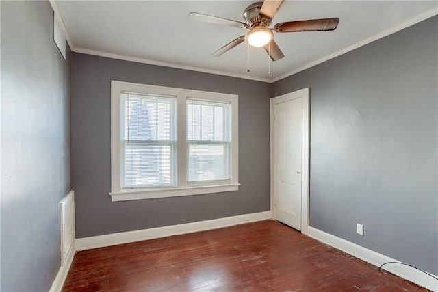 empty room featuring dark wood-style flooring, a ceiling fan, baseboards, and ornamental molding