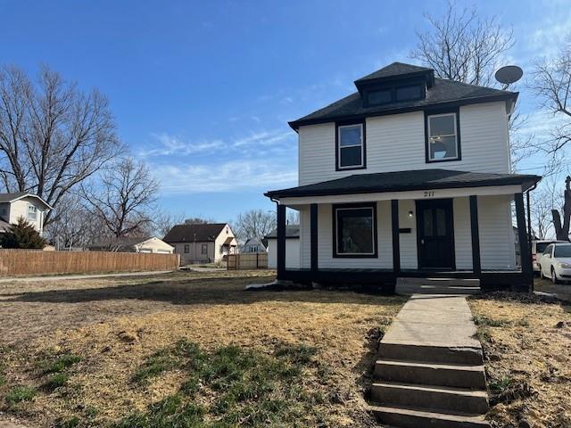 traditional style home with covered porch and fence