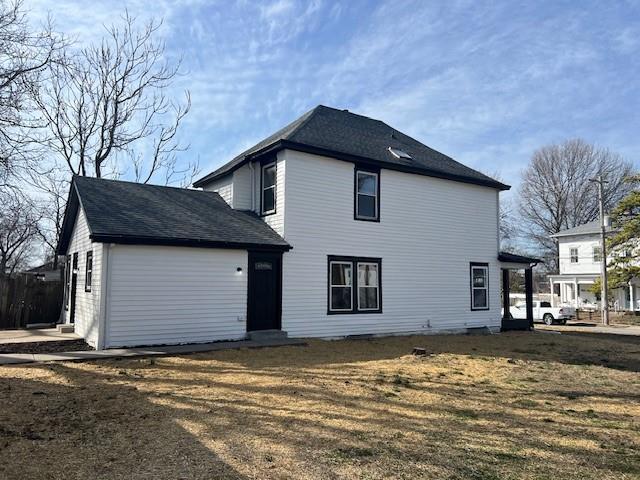 rear view of property featuring a lawn