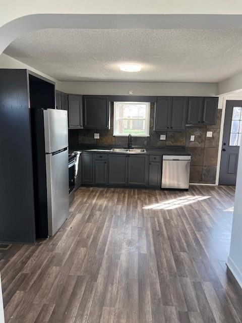 kitchen featuring a wealth of natural light, dark wood-style floors, stainless steel appliances, and a sink