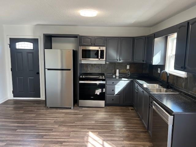 kitchen with dark countertops, appliances with stainless steel finishes, a wealth of natural light, and a sink