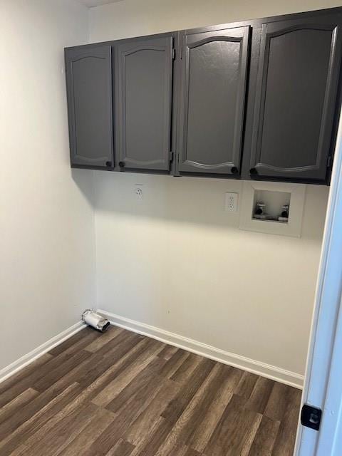 clothes washing area with dark wood finished floors, washer hookup, cabinet space, and baseboards