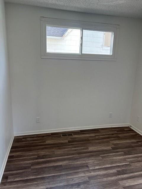 unfurnished room featuring dark wood finished floors, a textured ceiling, and a wealth of natural light