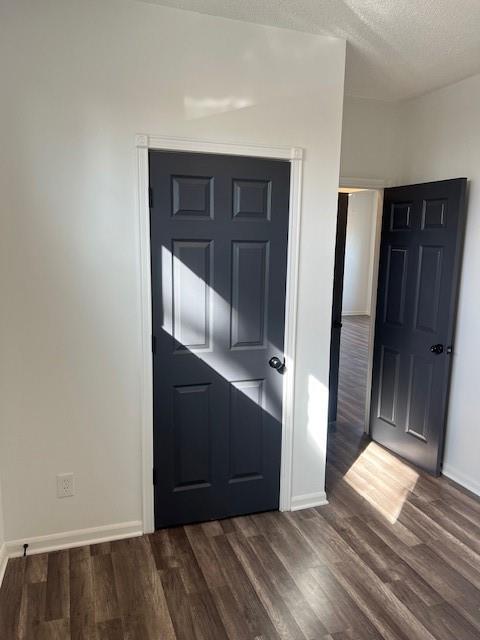 foyer entrance featuring baseboards, a textured ceiling, and dark wood-style floors