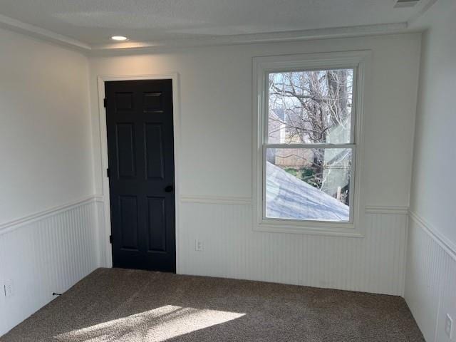 empty room featuring a wainscoted wall and carpet flooring